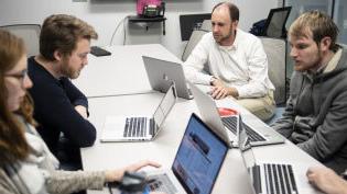 Students with laptops studying at a table.