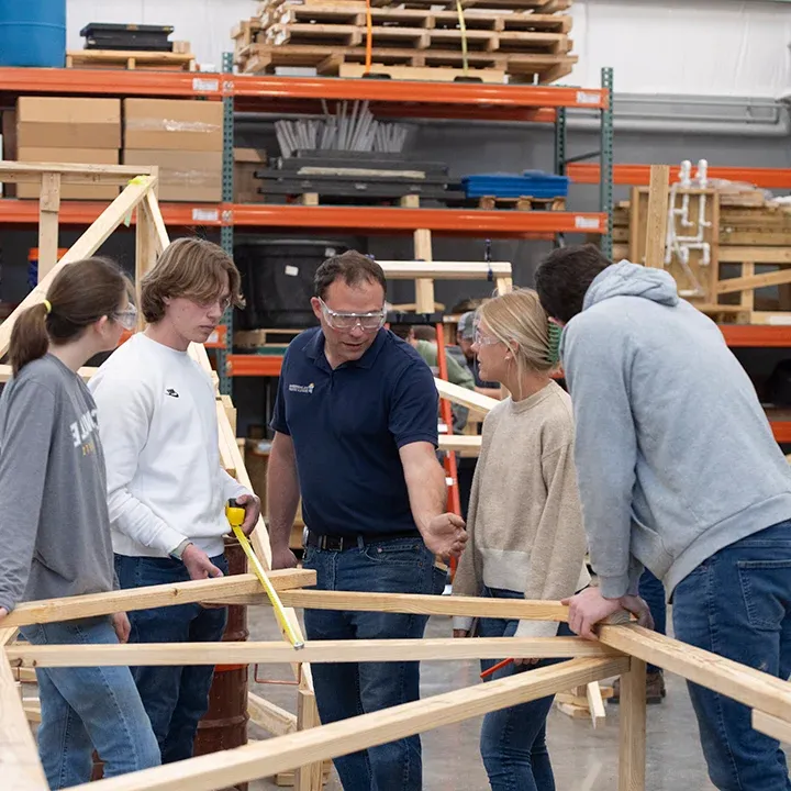 Professor instructing mechanical engineering students building a wooden structure.