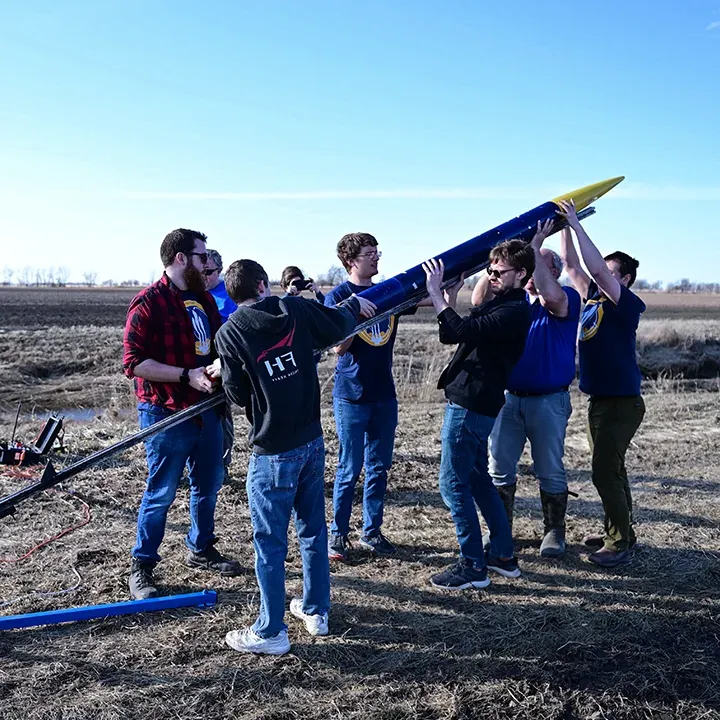 Small group of students and professors setting up rocket