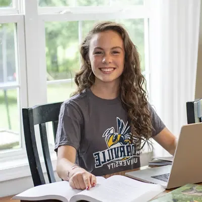 Female student doing homework at a dining room table.