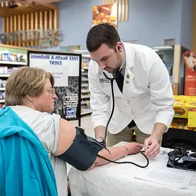 Pharmacist using a blood pressure cuff and stethoscope to care for a patient.