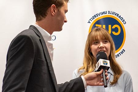 Man interviewing women with the Cedarville University Entrepreneurship CUE logo in the background